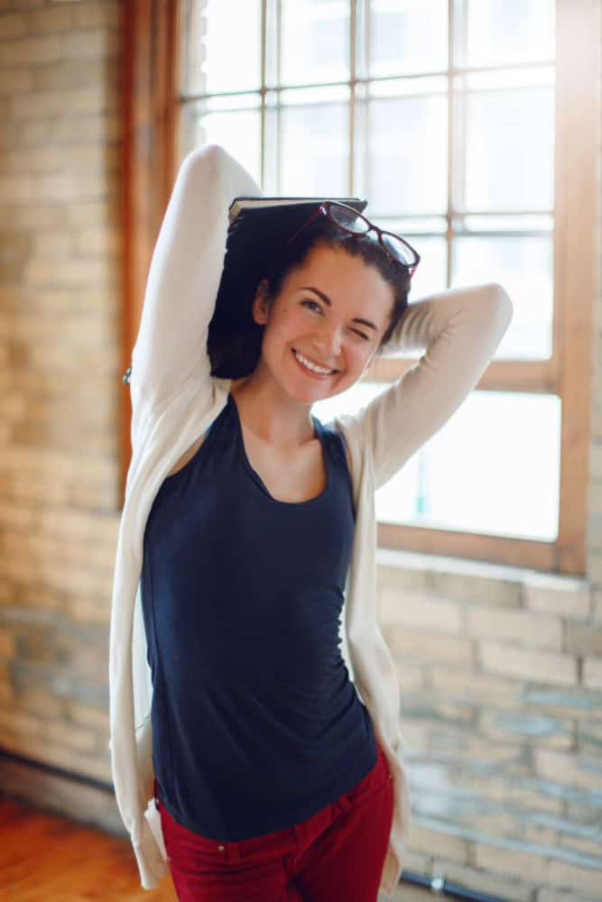 A woman raising her hands over her head and winking with a smile