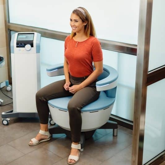 Woman sitting on the Emsella Chair in a clinic